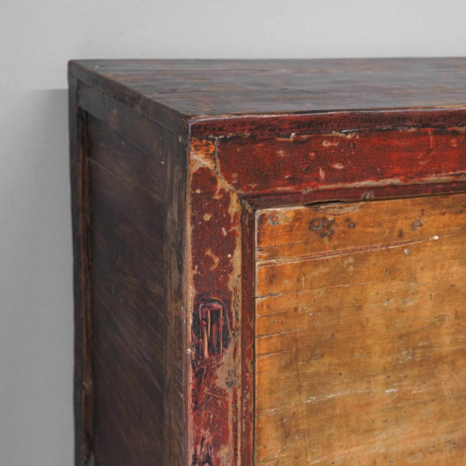 Close-up of a wooden cabinet with visible wear and tear on a gray background